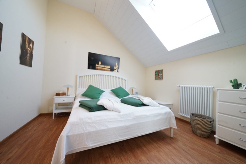 Schlafzimmer mit Doppelbett unter dem Dachfenster